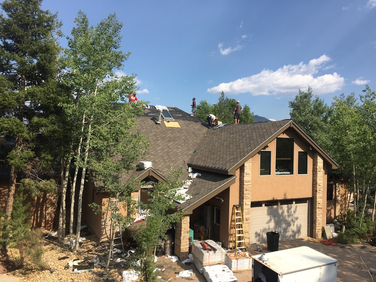 Crew installing shingles on a two-story home